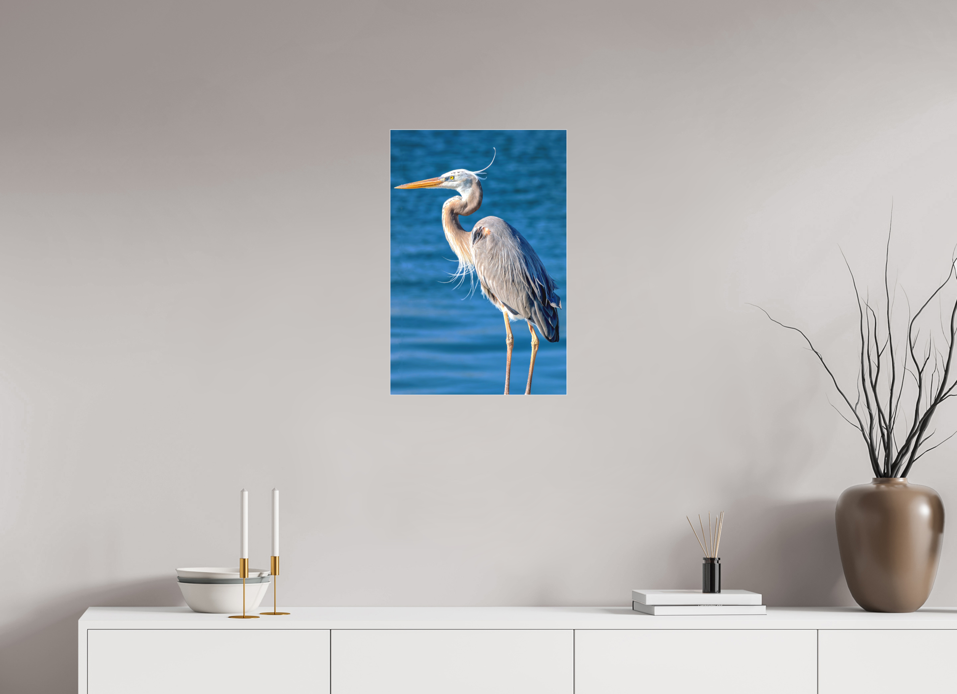 16x24" 'Standing Blue Heron' print in a slimline aluminum frame with matte acrylic, styled on a wall above a credenza with books and candlesticks.