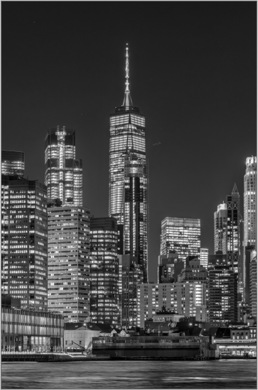 Black and white cityscape of illuminated skyscrapers at night.