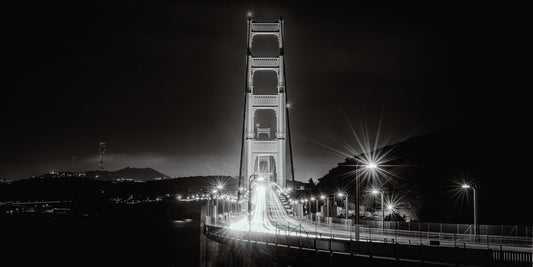 Starbursts — Golden Gate Bridge at night with traffic light trails and starburst streetlamps beneath its illuminated North tower, black-and-white fine art photography print by Richard H Knight