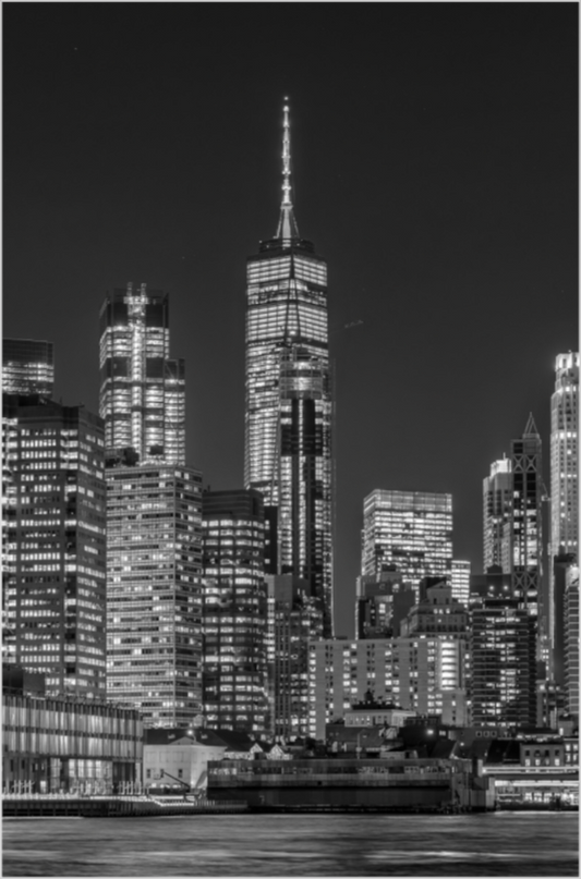 Black and white cityscape of a skyscraper at night with illuminated windows.