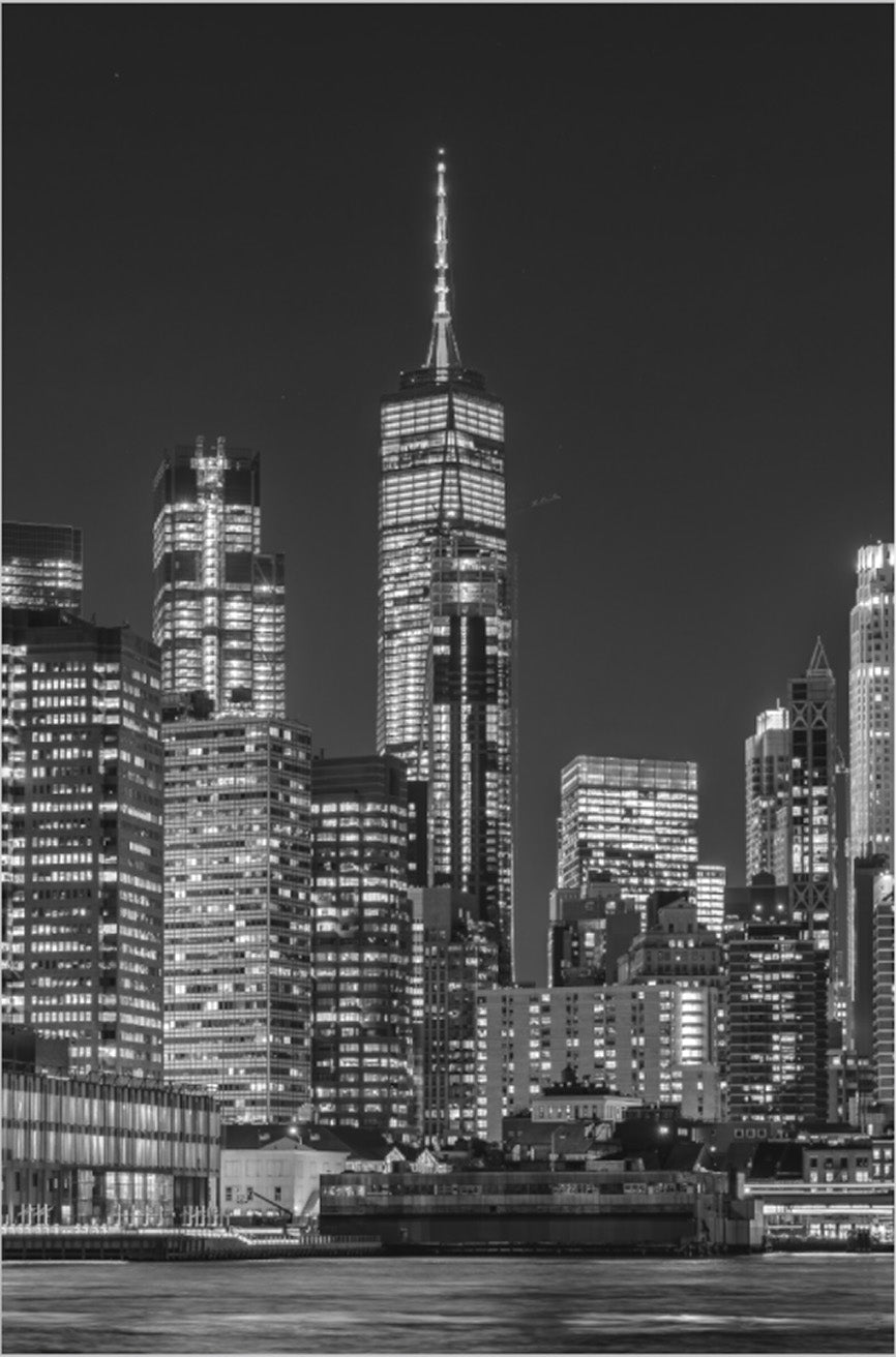 Manhattan at Night — Illuminated Lower Manhattan skyline with One World Trade Center rising above the East River, framed black-and-white fine art photography print by Richard H Knight