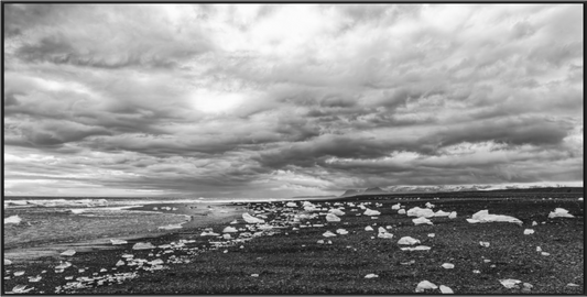 Beach Diamonds — Luminous ice fragments on black volcanic sand beneath a brooding sky at Diamond Beach, Iceland, framed B&W fine art photography print by Richard H Knight