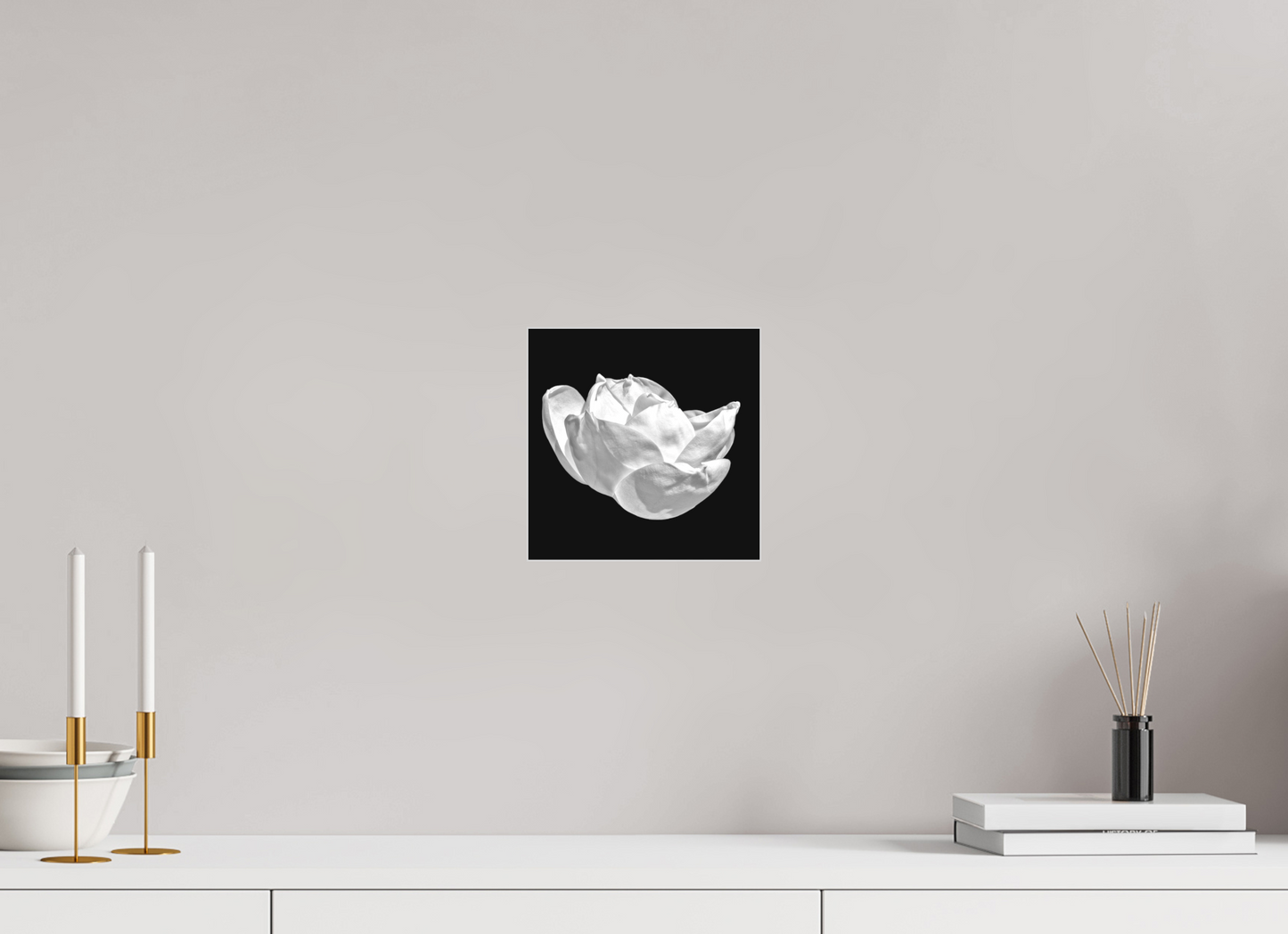 Decorative wall art of a white flower on a black background in a modern interior setting.