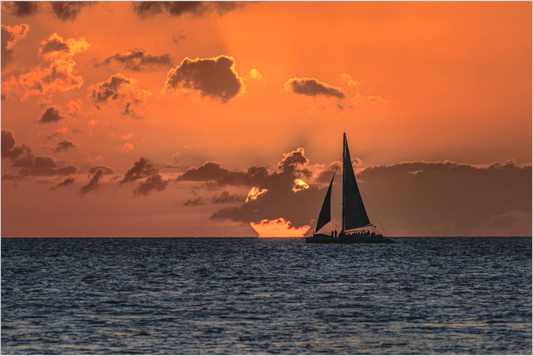 Sailboat on the water with a dramatic orange sunset sky